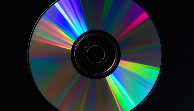 Compact disc showing vibrant rainbow light reflection on circular metallic surface against dark black background viewed from directly above
