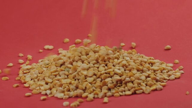 Split Yellow Peas Pouring into a Pile on Red Background in Slow Motion