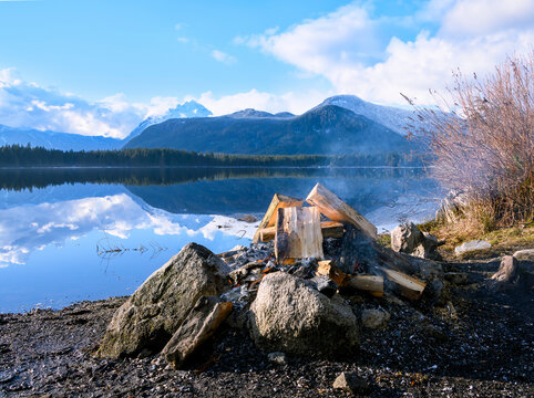 Campfire by the lake with mountains and clear sky in a natural setting