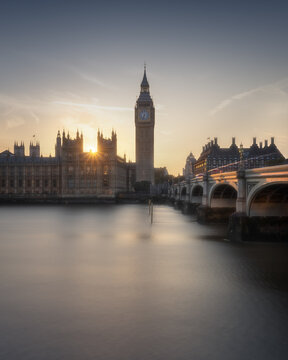 View of Big Ben and the Palace of Westminster at sunset with the calm River Thames in the foreground in London, England, United Kingdom.