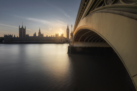 View of the Palace of Westminster and Big Ben at sunset from under Westminster Bridge, with the River Thames in the foreground in London, England, United Kingdom.