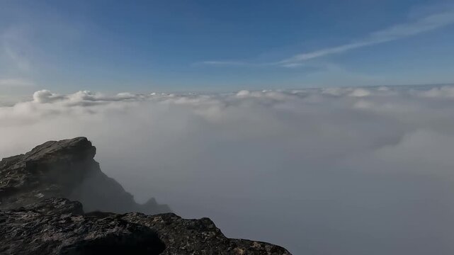 Dramatic Rocky Peak Rising Above Sea of Clouds with Blue Sky in Senja Island Northern Norway