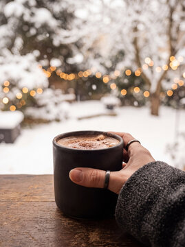 Hand Holding Hot Chocolate Mug in Snowy Winter Setting