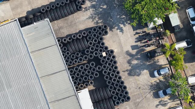 Stacks of car tires arranged neatly in an outdoor storage area on a bright afternoon in Indonesia