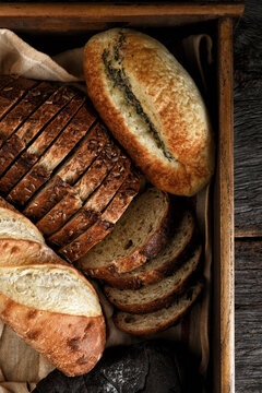 Bread Still Life. An assortment of different breads in a wooden box on a rustic wood table.