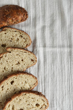 Bread Still Life. Fresh baked lices of a multi grain loaf of bread arranged on a kitchen towel, with copy space.