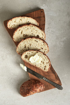 Bread Still Life. Fresh baked lices of a multi grain loaf of bread arranged on a cutting board with a knife and butter.