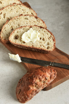 Bread Still Life. Fresh baked lices of a multi grain loaf of bread arranged on a cutting board with a knife and butter.