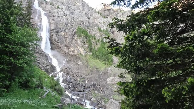 Engstligen Waterfall Cascading Down Rocky Alpine Cliff Framed by Pine Trees in Adelboden Switzerland