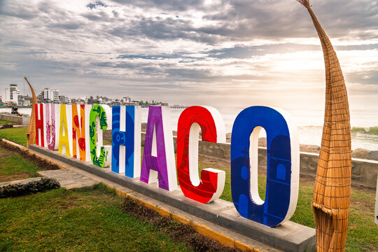 Huanchaco, Peru - January 10, 2024: Colorful Huanchaco sign with traditional reed boats and Pacific Ocean at sunset