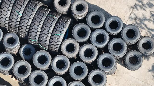 Many rubber tires stored for heavy mining equipment in a sunny open industrial area