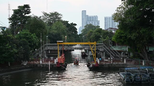 Canal boat passes water gate near Wat Paknam Phasi Charoen