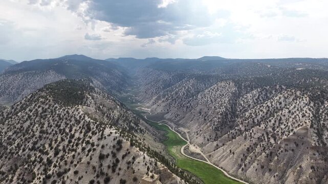Aerial of mountain valley and winding river through Duchesne County Utah with arid scrubcovered slopes dense forested areas and agricultural fields