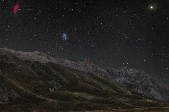 View of the starry night sky over the rugged mountain landscape of Lago Pietranzoni in L'Aquila, Abruzzo, Italy.