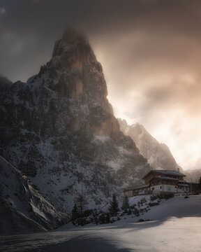 View of the snow-covered Cimon della Pala mountain peak towering over a mountain lodge at Passo Rolle, Trentino-Alto Adige, Italy.