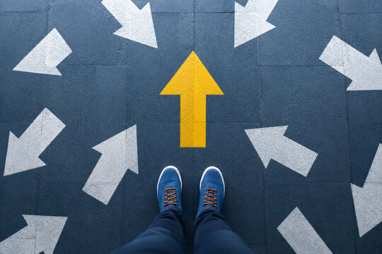 AI generated person facing bold yellow arrow among multiple white arrows representing choice direction decision making leadership focus strategy moving forward