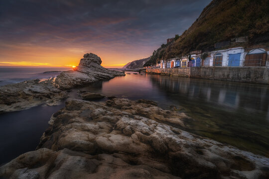 View of the Sedia del Papa rock formation at sunset with colorful caves along the cliffside at Passetto beach in Ancona, Marche, Italy.