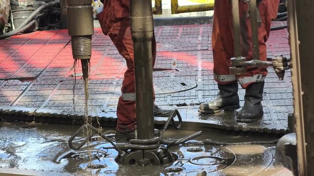 Rig crew perform pulling of of hole drill string with oil based mud on the rig floor. Trip out of hole.