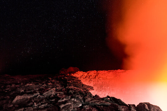 View of the glowing lava lake at Erta Ale volcano under a starry night sky in Ethiopia.