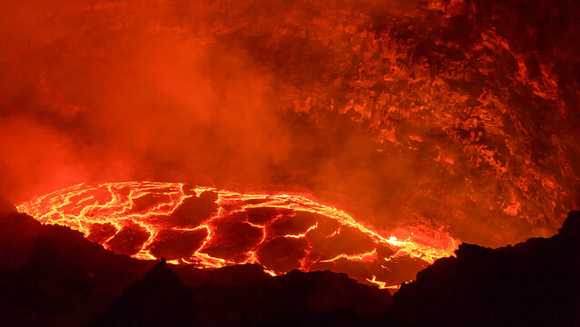 View of the glowing lava lake inside the Erta Ale volcano crater with molten rock and volcanic smoke in Erta Ale, Ethiopia.