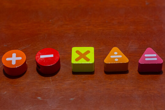 Row of wooden colorful blocks featuring basic math symbols including addition, subtraction, multiplication, division, and equal signs for elementary education