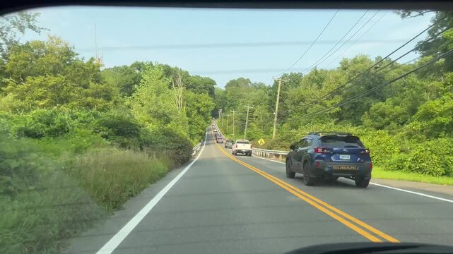 Rear window view of driving on rural road as cars pass