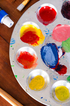 Close up of a paint palette with artist paint, brushes and tube of paint