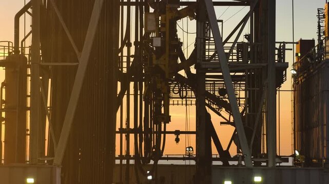 Top Drive System (TDS) in the derrick, offshore Jack-Up Rig Mast Structure during sunset time in the middle of the ocean