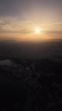 Aerial view of Malaga bullring (Plaza de Toros de la Malagueta) illuminated at sunset. Cinematic drone shot of the coastal arena, Mediterranean sea, and city skyline during golden hour.