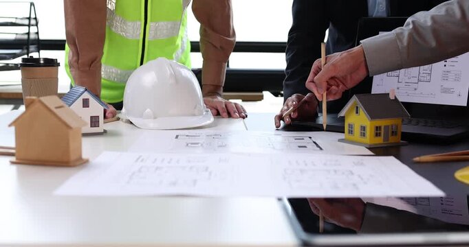 Architects and engineers discussing house model with blueprints, planning construction project and real estate development