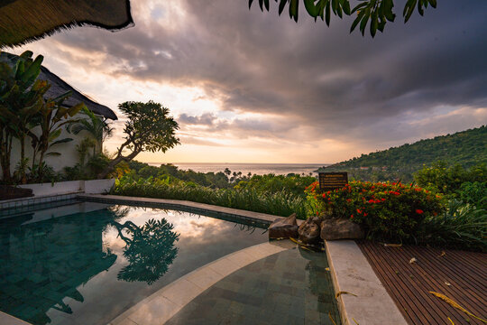View of The Griya Villas and Spa with a private swimming pool overlooking the ocean at sunset, surrounded by lush tropical greenery in Kecamatan Abang, Bali, Indonesia.