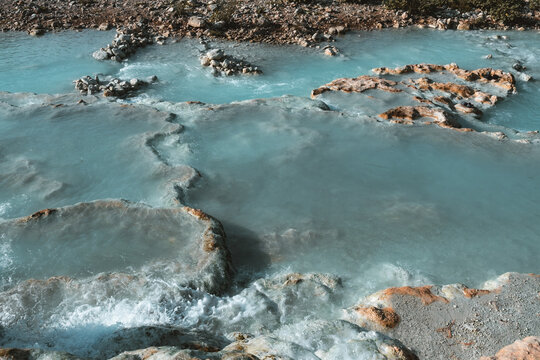 Aerial view of the thermal hot springs in Saturnia, featuring cascading turquoise pools, limestone terraces, and flowing mineral water in Saturnia, Tuscany, Italy.