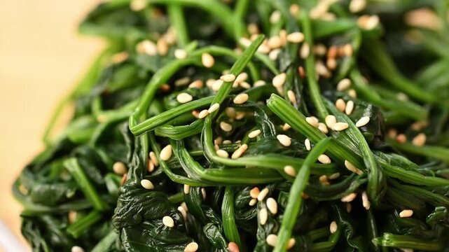 Close-up of Korean spinach salad (Segeumchi namul) in a bowl, slowly rotaing
