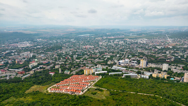 Aerial view of a sprawling city of Pyatigorsk surrounded by green forest, Russia. Modern residential complex with red roofs in the foreground. Urban landscape