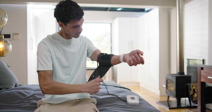 African American man on bed grabbing cuff and monitor, fitting on arm and taking blood pressure