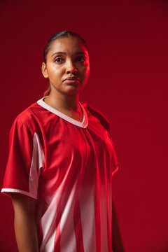 African American adult woman posing in studio wearing red white sports jersey, looking right