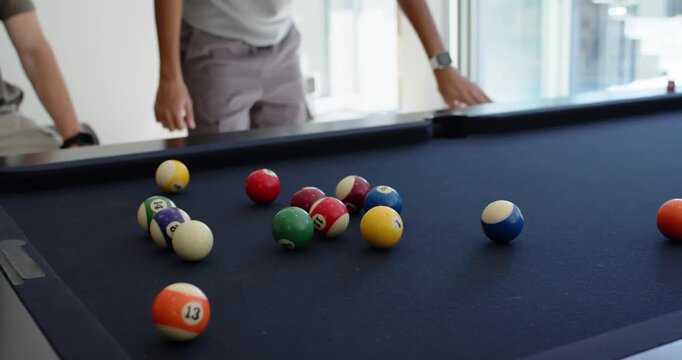 Male friends playing pool at home, left friend breaking balls, center friend watching and gesturing