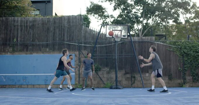 Diverse teammates on outdoor court, defender closing out, purple-tank lobbing orange ball to score