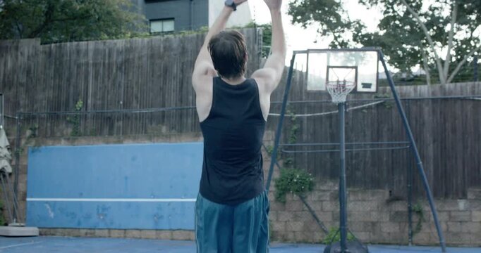 Male friends practicing in yard, shooter in black tank after setup taking shot, friend chasing ball