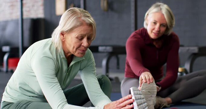 Senior women stretching on gym mats left woman smiling reaching shoe mirroring hamstring stretching