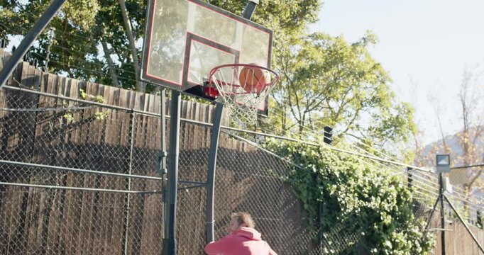 Two men playing yard hoop, pink hoodie driving, leaping, ball rimming, getting ball holding smiling