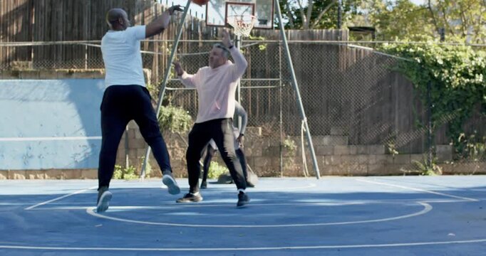 Diverse males on court, white tee dribbling after pink hoodie pressing, red shooting, gray dunking