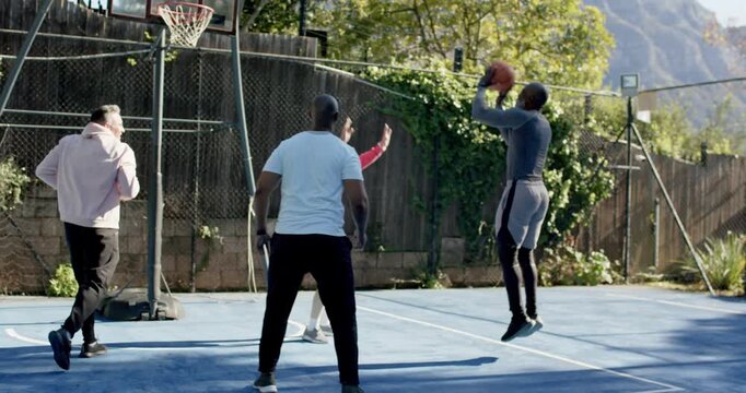 Male friends moving midcourt, shooter gray dribbling ball toward hoop on blue court playing pickup