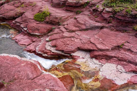 View of the red argillite rock formations and flowing stream in Waterton Lakes National Park of Canada in Waterton Park, Alberta, Canada.