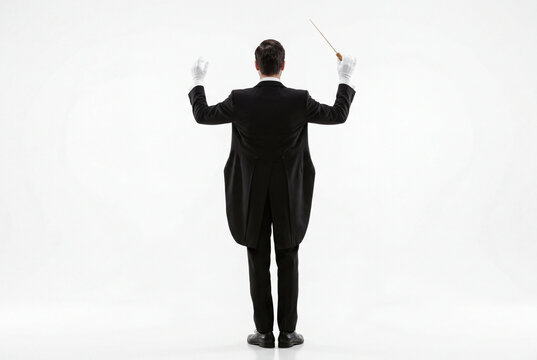 Male orchestra conductor viewed from behind holding a raised baton