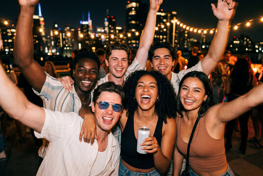 Diverse group of friends smiling and celebrating on a rooftop at night
