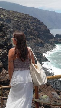 Beautiful woman admiring volcanic coastline of el hierro
