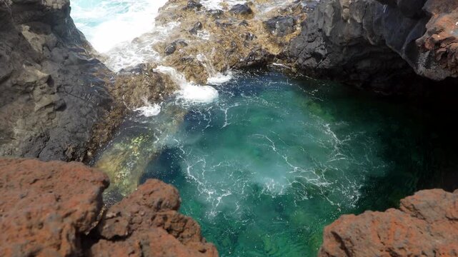 Woman jumping into natural volcanic pool in el hierro