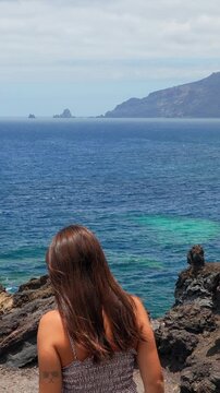 Young woman enjoying ocean view from volcanic cliffs in el hierro