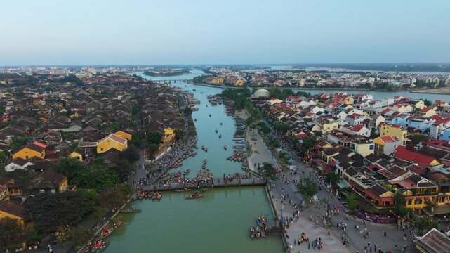 Crowded Quay With Lively Marketplace Scene. Aerial View Of Bustling Market Boats And Vibrant Street Life. High Above Crowded Riverside Market Showing Lively Boats And Colorful Shop Roofs